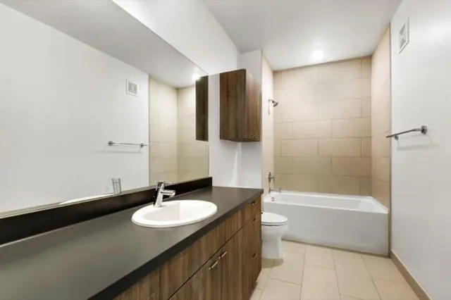 a bathroom with a granite countertop sink a toilet a shower and a mirror