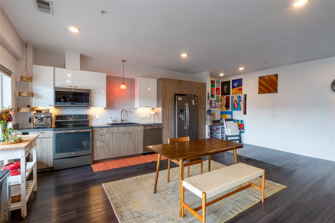 4361 South Congress Avenue, Unit 314 Austin, TX 78745 - Photo 3 of 25 a kitchen with stainless steel appliances kitchen island granite countertop a refrigerator a stove top oven a sink dishwasher and white cabinets with wooden floor
