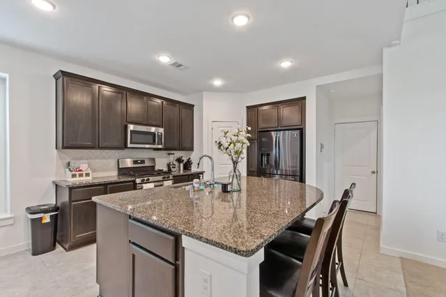 a kitchen with kitchen island granite countertop a sink a counter space appliances and cabinets