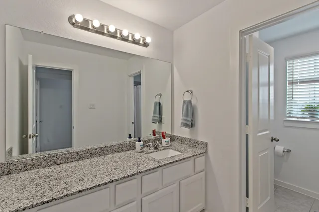 a bathroom with a granite countertop sink and a mirror