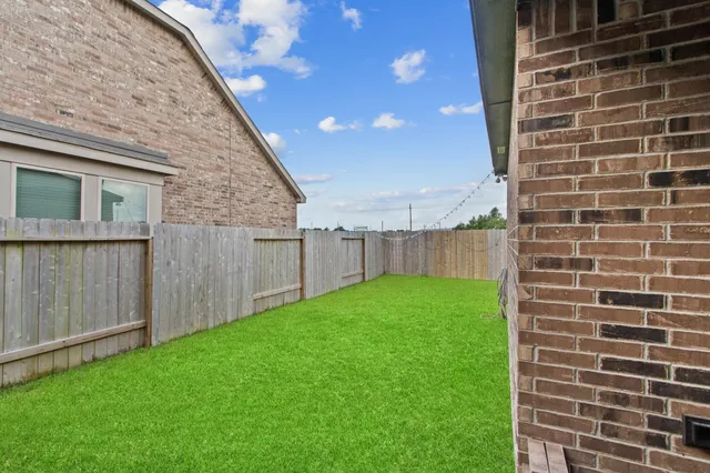 a view of a backyard with brick wall and a fence