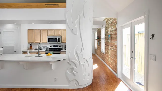 a view of a kitchen with kitchen island a sink appliances wooden floor and a window
