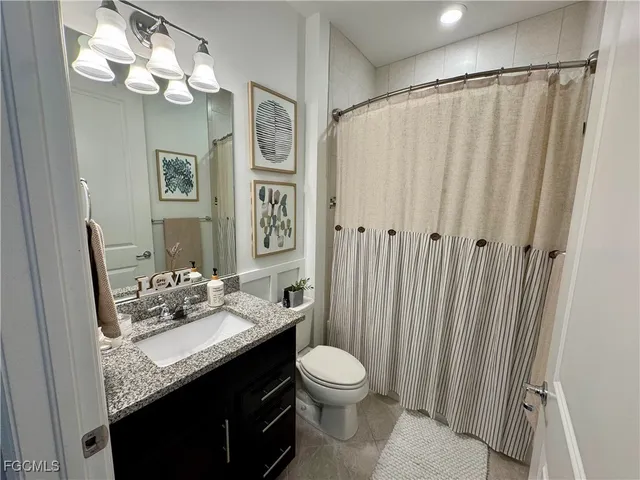 a bathroom with a granite countertop sink a toilet and a mirror