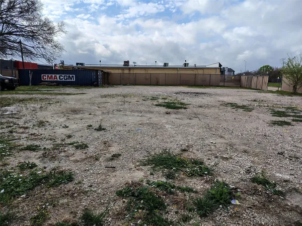a view of a dry yard with a house in the background