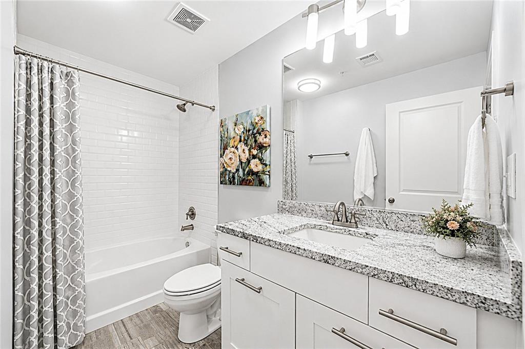 3300 Windy Ridge Parkway Southeast, Unit 1112 Atlanta, GA 30339 - Photo 23 of 43 a bathroom with a granite countertop sink a toilet a mirror a bathtub and shower