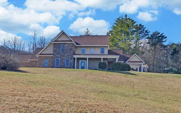 a view of a house with a yard and large tree
