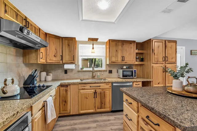 a kitchen with stainless steel appliances kitchen island granite countertop a sink stove and cabinets
