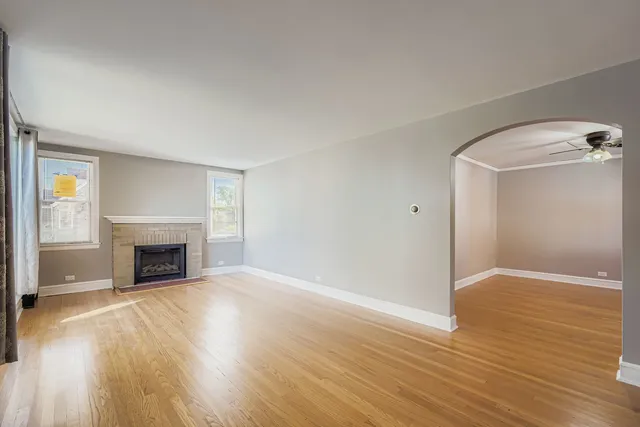 an empty room with wooden floor fireplace and windows
