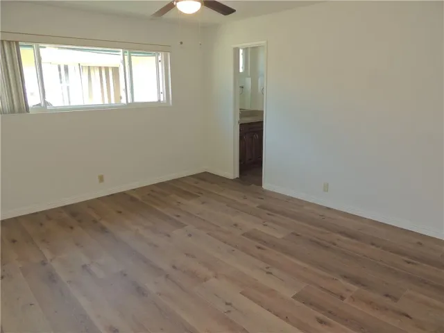 an empty room with wooden floor cabinet and windows