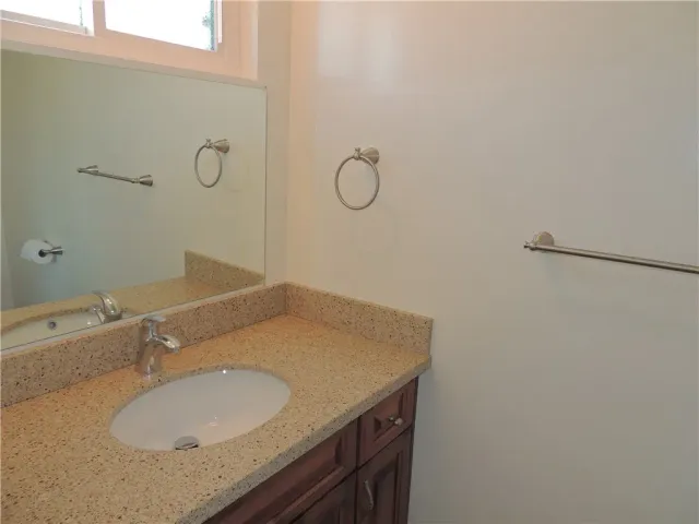 a bathroom with a granite countertop sink and a mirror