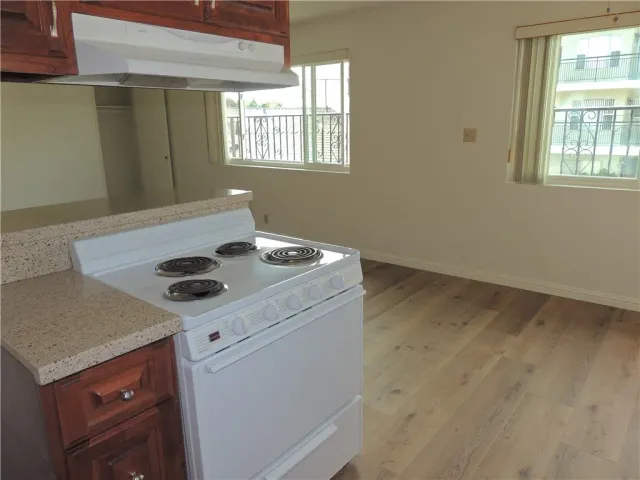 a view of kitchen cabinets a stove a sink and a window