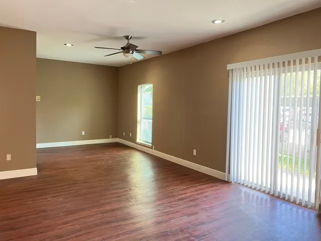 a view of an empty room with a window and wooden floor