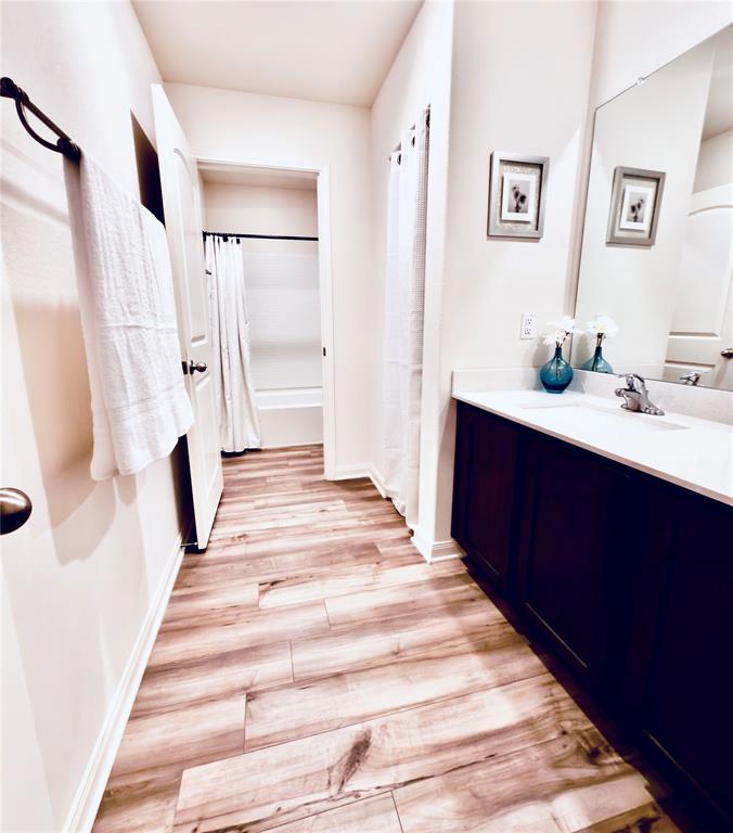 196 Cattlemans Crk Road West Newark, TX 76071 - Photo 21 of 31 Bathroom featuring wood-finish plank flooring, a dark wood-finish vanity with a white countertop, an integrated sink, and a framed mirror