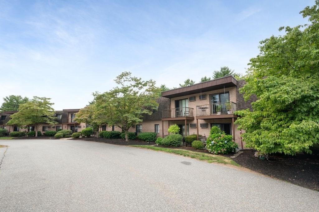 147 Sylvan Street, Unit 18B Danvers, MA 01923 - Photo 2 of 24 a front view of a house with a yard and trees