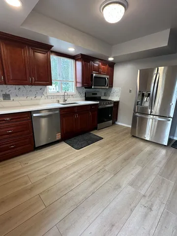 a open kitchen with stainless steel appliances granite countertop a stove top oven a sink dishwasher a refrigerator and cabinets with wooden floor