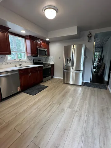 a kitchen with stainless steel appliances kitchen island granite countertop a refrigerator a sink a stove and oven