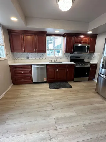 a kitchen with stainless steel appliances kitchen island granite countertop a stove a sink and a microwave