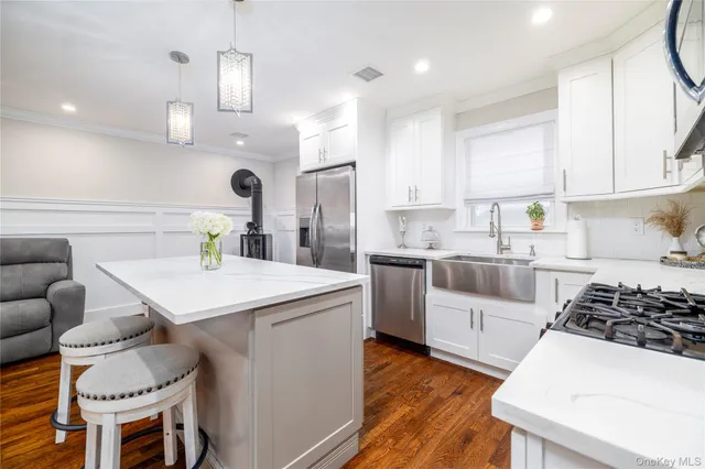 a kitchen with a sink a stove a refrigerator and white cabinets