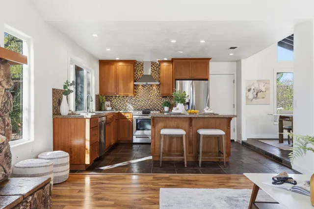 a kitchen with stainless steel appliances wooden floor dining table and chairs