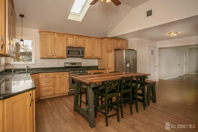 a kitchen with a table chairs a sink dishwasher stove and cabinets with wooden floor