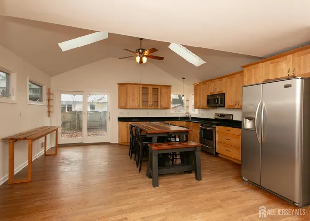 a kitchen with stainless steel appliances a refrigerator a stove a sink dishwasher with a dining table and chairs