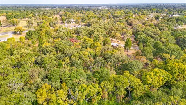 an aerial view of residential houses with outdoor space and trees
