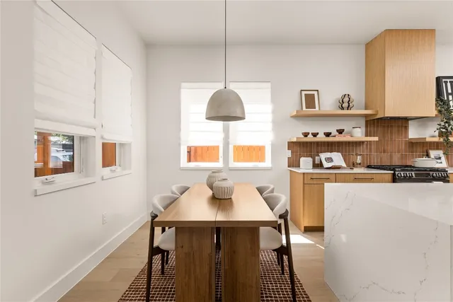 a kitchen with stainless steel appliances a dining table chairs and a refrigerator