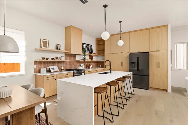 a kitchen with stainless steel appliances a stove a sink a refrigerator a center island a stove and a refrigerator