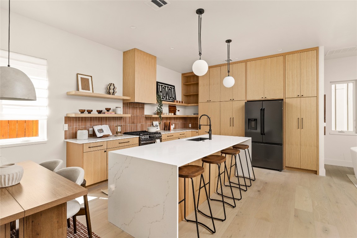 4530 Clawson Road, Unit 1 Austin, TX 78745 - Photo 17 of 24 Kitchen featuring light brown cabinetry, a kitchen breakfast bar, black appliances, tasteful backsplash, and decorative light fixtures