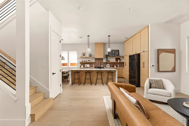 a living room with stainless steel appliances furniture and a kitchen view