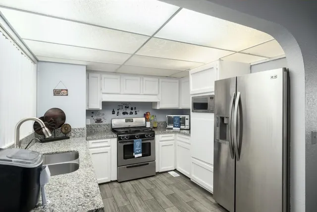 a kitchen with stainless steel appliances a stove a sink dishwasher a refrigerator and cabinets with wooden floor