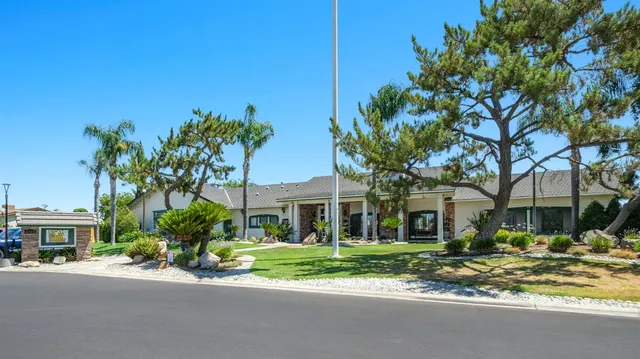 a view of a white house with a large tree and a yard