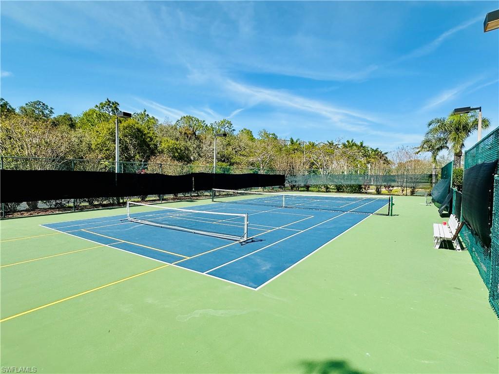 1820 Florida Club Circle, Unit 2210 Naples, FL 34112 - Photo 29 of 37 View of tennis court featuring community basketball court and view of wooded area