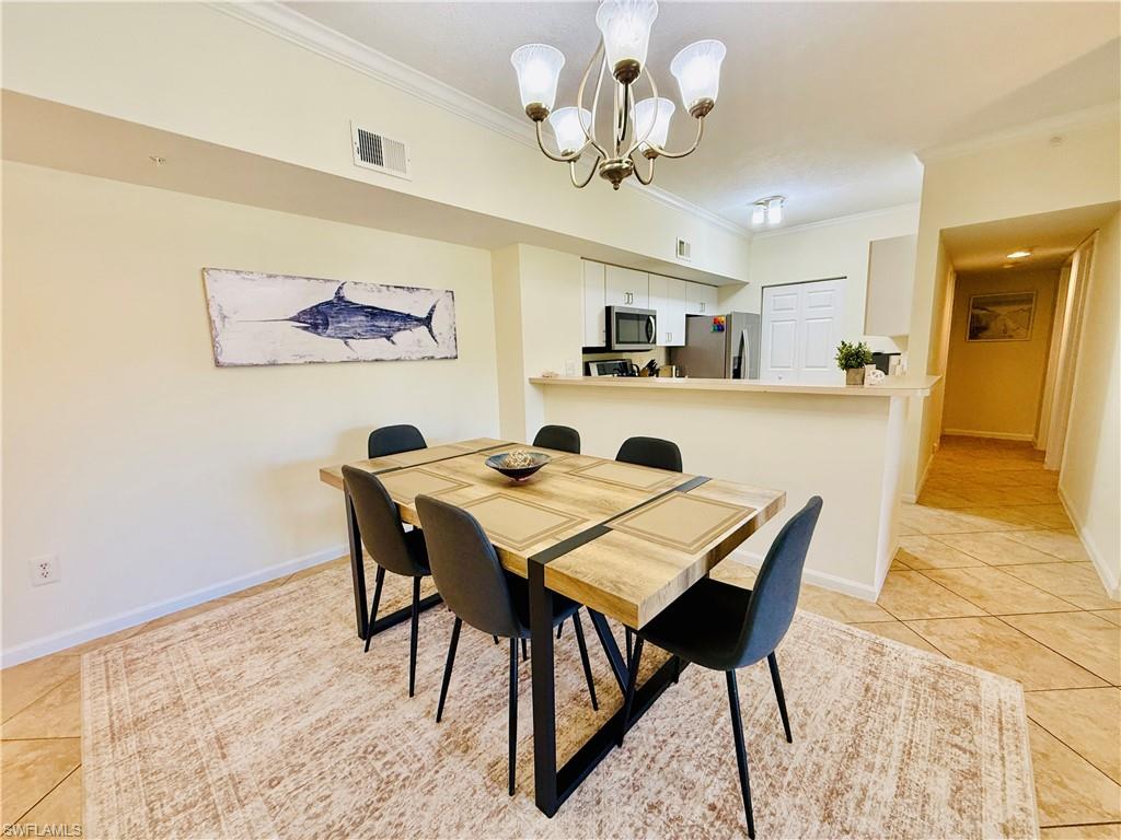 1820 Florida Club Circle, Unit 2210 Naples, FL 34112 - Photo 9 of 37 Dining room with light tile patterned floors, crown molding, and a chandelier