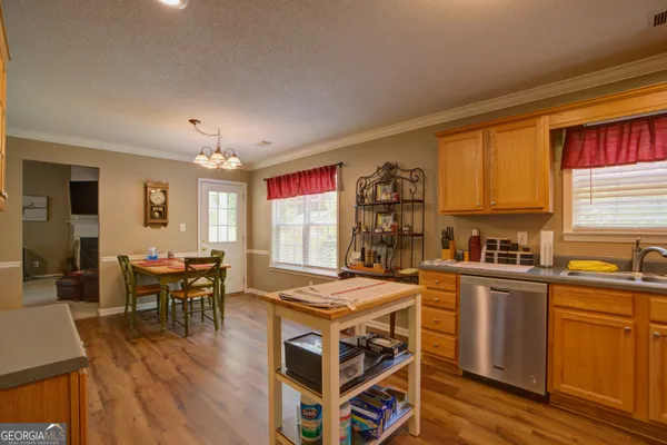 a kitchen with stainless steel appliances a stove a sink dishwasher a dining table and chairs with wooden floor