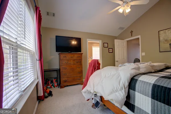 a bedroom with a bed and a flat tv screen on dresser