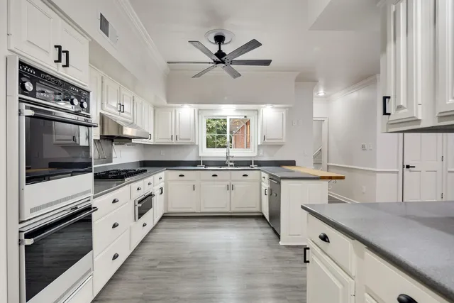a kitchen with granite countertop a sink appliances cabinets and a window