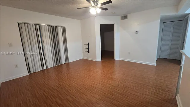 an empty room with wooden floor and a ceiling fan