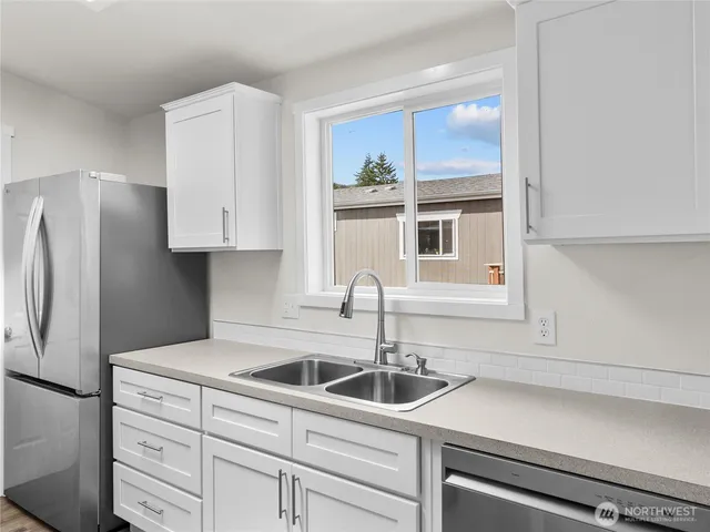 a kitchen with stainless steel appliances a sink dishwasher a refrigerator and cabinets