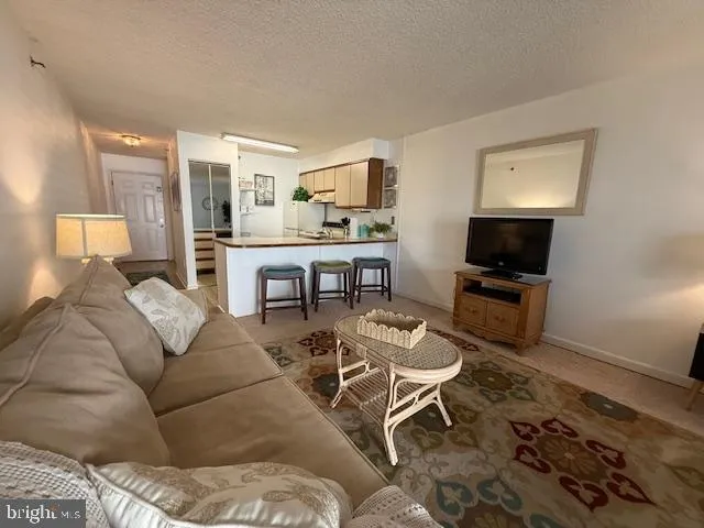 a living room with furniture a flat screen tv and kitchen view