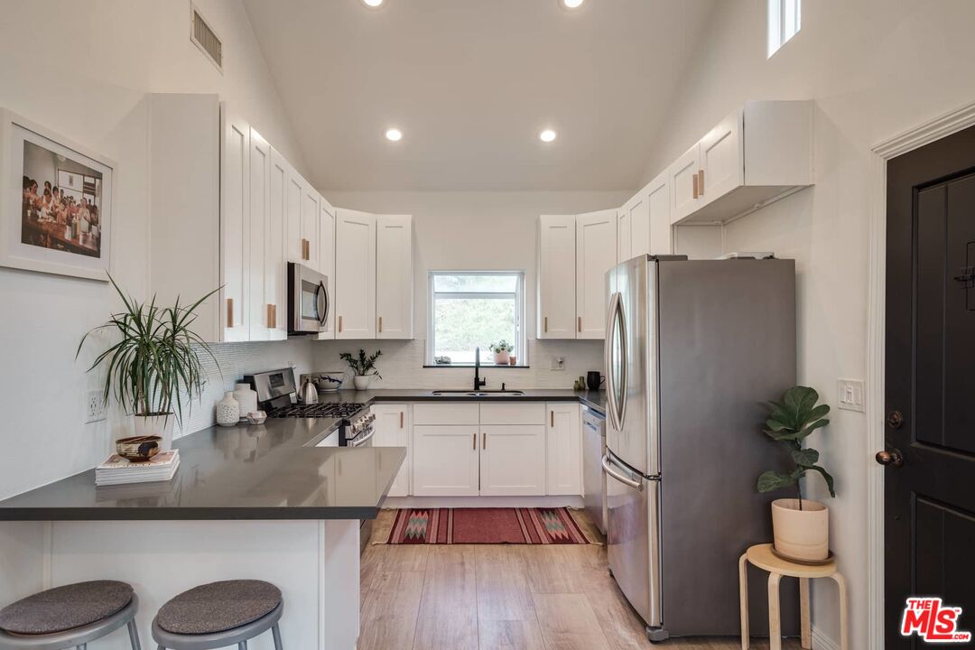 4535 Dudley Drive Los Angeles, CA 90032 - Photo 5 of 24 a kitchen with granite countertop a refrigerator a stove a sink and white cabinets with wooden floor
