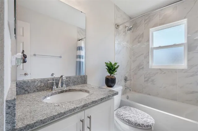 a bathroom with a granite countertop sink a toilet and bathtub