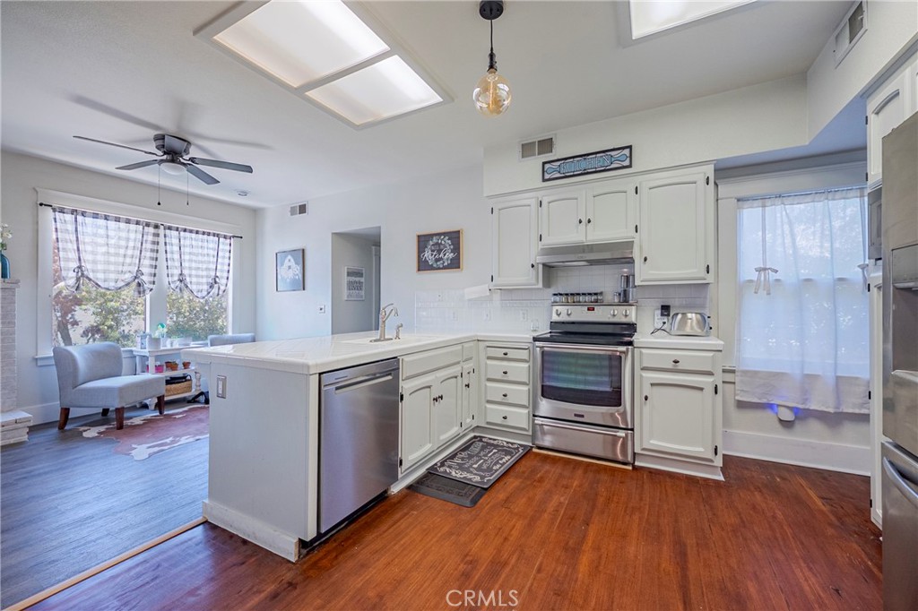 14625 Le Grand Road Le Grand, CA 95333 - Photo 29 of 60 a kitchen with stainless steel appliances a stove a sink dishwasher a refrigerator and a dining table with wooden floor