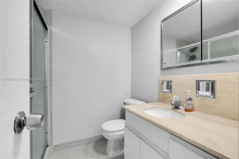 a bathroom with a granite countertop sink mirror vanity and toilet
