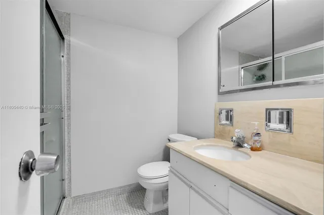 a bathroom with a granite countertop sink mirror vanity and toilet