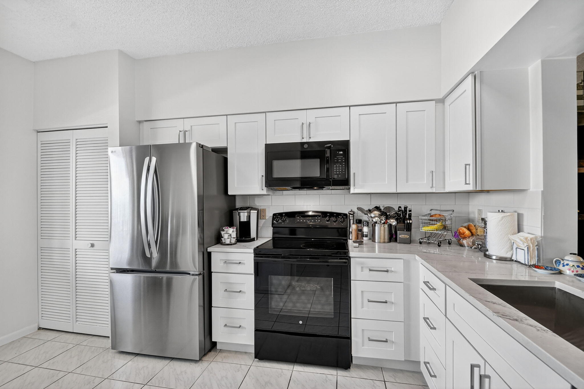 6193 Pointe Regal Circle, Unit 402 Delray Beach, FL 33484 - Photo 8 of 104 a kitchen with refrigerator a microwave a sink and cabinets