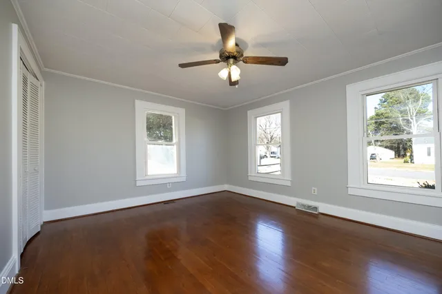 a view of an empty room with wooden floor and a window