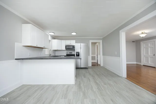 a kitchen with stainless steel appliances granite countertop a refrigerator sink and white cabinets