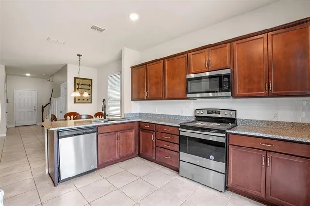 a kitchen with stainless steel appliances granite countertop a stove top oven a sink dishwasher and a microwave oven on the blue kitchen countertops
