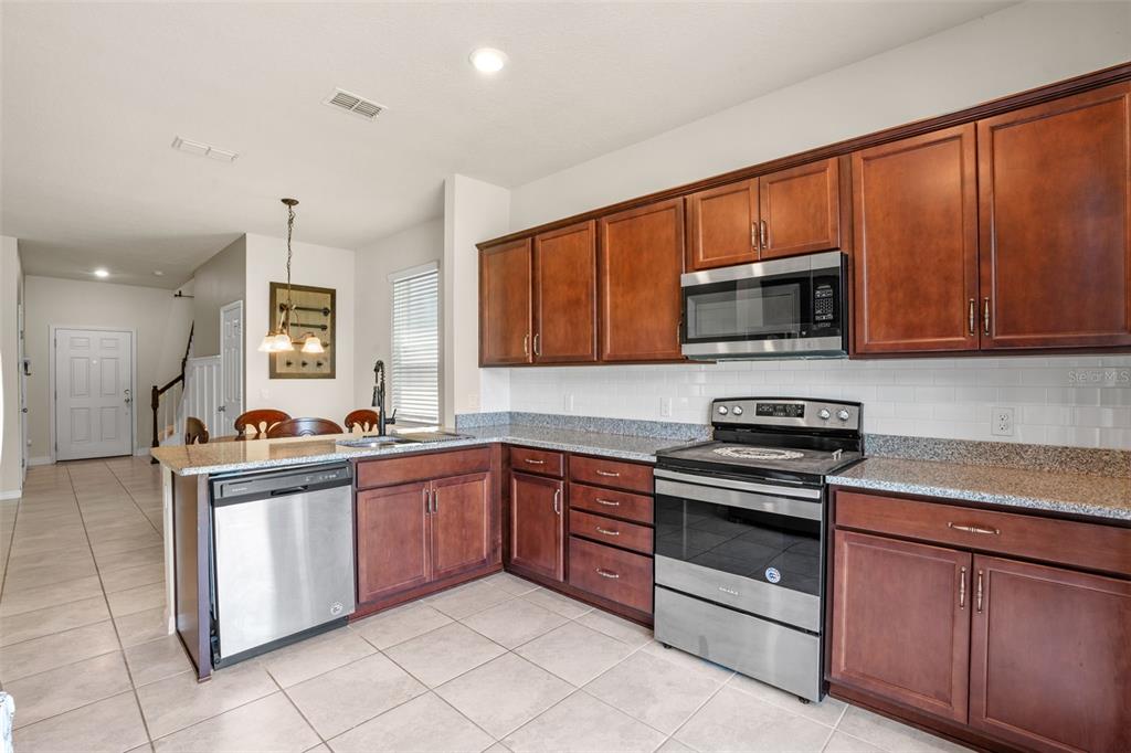 5164 Chickadee Street St. Cloud, FL 34771 - Photo 8 of 35 a kitchen with stainless steel appliances granite countertop a stove top oven a sink dishwasher and a microwave oven on the blue kitchen countertops